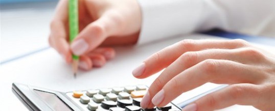 Close-up of a person using a calculator and writing on paper, representing the process of estimating a realistic settlement through an SBA Loan Offer in Compromise (OIC) calculator to determine how much a borrower can afford to pay toward resolving defaulted SBA debt.