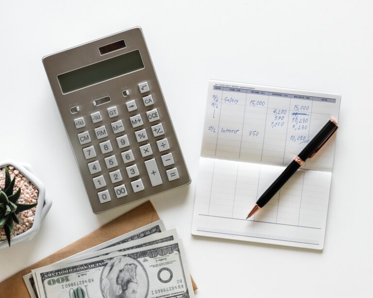Calculator, cash and a handwritten budget ledger on a desk, illustrating bootstrapping a business, managing cash flow and the financial strain that can quietly kill a growing company.