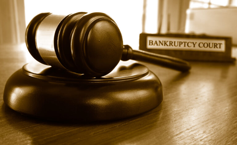 Judge’s gavel on a desk beside a bankruptcy court sign, illustrating what to know before advising your client to file bankruptcy.
