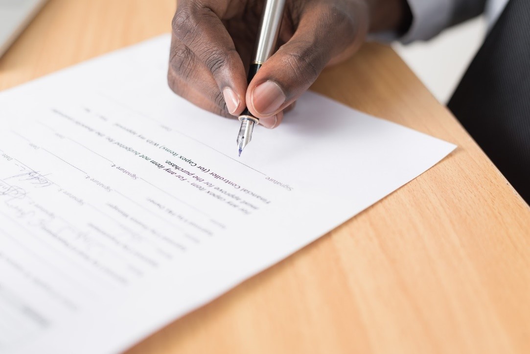 Close-up of a business owner signing a loan document, illustrating the considerations around when it may be ethical to not pay a loan.
